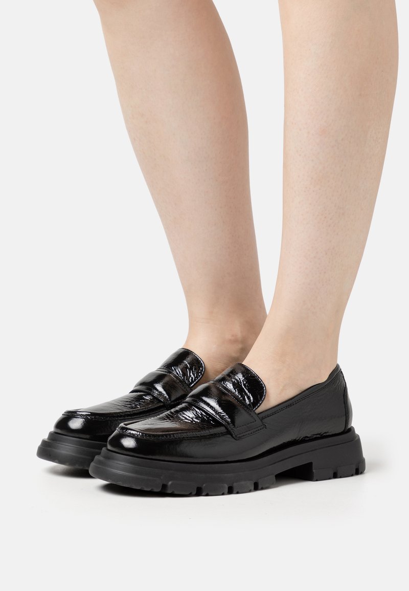 Zwarte gepatineerde leren loafers met een stevige rubberen zool en een ronde neus. Heeft twee banden over de wreef, wat textuur en detail toevoegt.