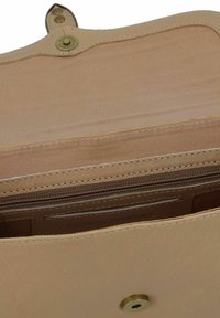 Interno di una borsa in pelle beige con texture liscia, dotata di una tasca con cerniera e una chiusura a scatto. Logo visibile sull'imbottitura interna.
