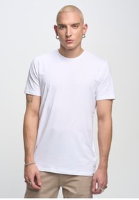 Witte katoenen t-shirt met een ronde hals, korte mouwen en een gladde textuur, met een getailleerde pasvorm en minimale branding.