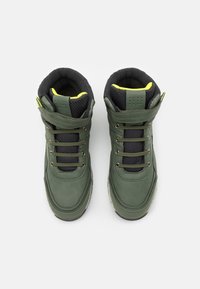 Baskets montantes en cuir vert avec doublure en mesh noir, présentant des lacets noirs, une semelle grise et des accents jaune fluo au niveau du col.