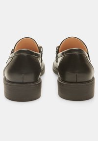 Černá kožená bota s hladkým povrchem, nízkým zúženým podpatkem a minimalistickým zadním designem. Obsahuje jemný šev a zakřivený siluetu.
