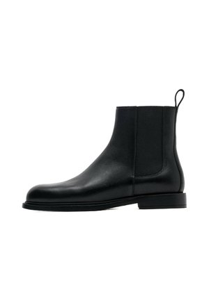 Bottine Chelsea en cuir noir avec panneau latéral élastique et languette à l'arrière, petit talon et bout arrondi.