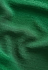 Groene stof met een gladde textuur, die subtiele golven en variaties in tint vertoont, wat een rijke, dimensionale uitstraling creëert.