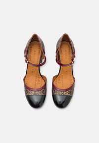 Chaussures bicolores avec un bout en cuir verni noir, des sangles bordeaux et une tige en motif texturé marron et noir. Talon plat.