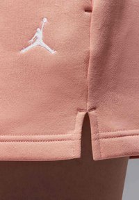Ljusrosa träningsshorts med en slät yta, som har en vit broderad Jumpman-logotyp och sidofickor för ökad rörlighet.