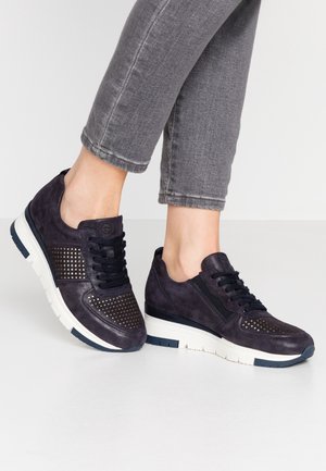 Marineblauwe suède sneakers met geperforeerde details, zwarte veters en witte rubberen zolen, voorzien van een strak ontwerp en contrasterende texturen.