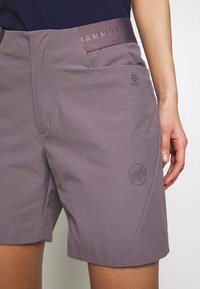 Lila shorts med en jämn struktur, med en sidficka och en logotryck. Midjebandet har en märkesaccent.