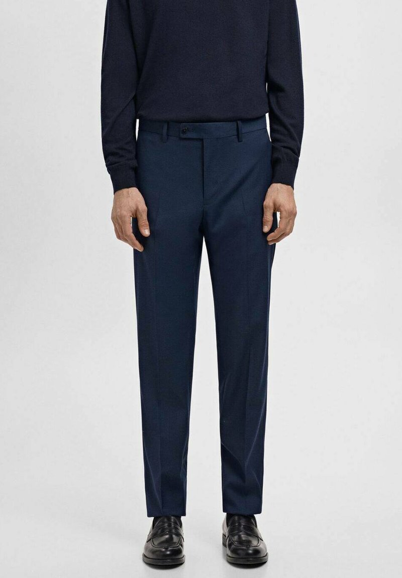 Granatowe, dopasowane spodnie o prostym kroju, z płaskim przodem, szlufkami na pasek i gładką fakturą, zestawione z czarnymi butami.