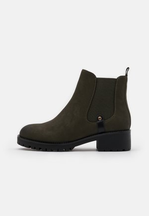 Bottine Chelsea en daim vert foncé avec panneau latéral élastique noir, languette noire et semelle noire épaisse avec un petit talon.