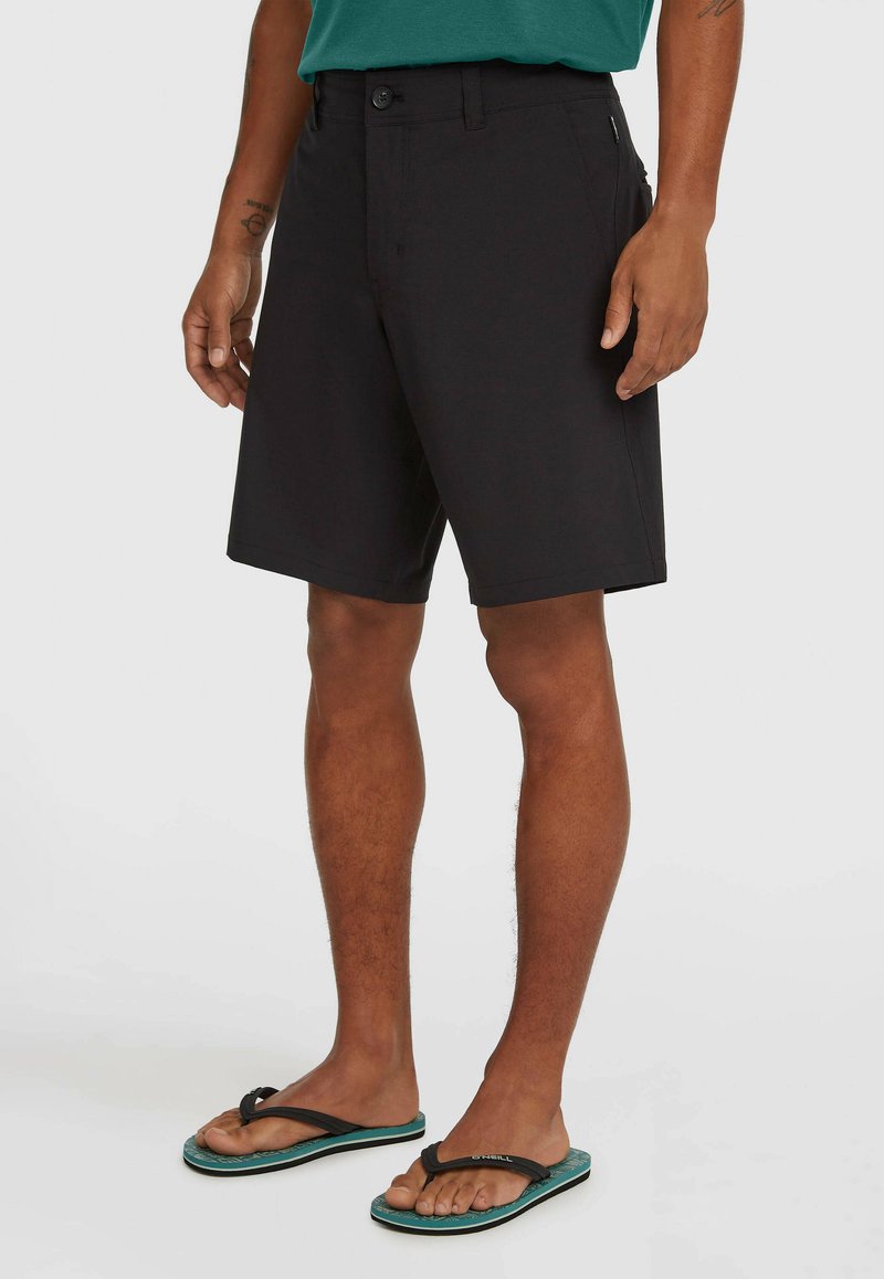 Čierne šortky s rovnou prednou stranou, zapínaním na gombík, bočnými vreckami a priamym strihom. Kombinované s čiernymi žabkami s modrozelenou podrážkou.