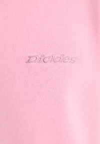 Ανοιχτό ροζ βαμβακερό T-shirt με τονικό κεντημένο λογότυπο "Dickies" στο μπροστινό μέρος. Λείος υφασμάτινος σχεδιασμός με κλασική στρογγυλή λαιμόκοψη.