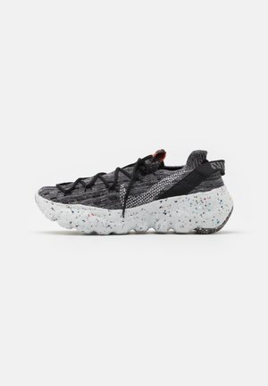 Baskets tricotées noires et grises avec des lacets noirs et une semelle épaisse blanche tachetée, conçues pour un usage décontracté ou sportif.