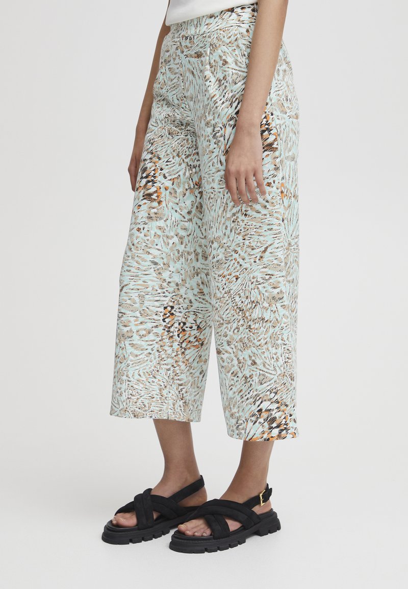 Pantalons amples à motifs de couleur menthe clair, ornés d'un mélange de motifs abstraits en beige et marron, fabriqués en tissu léger.
