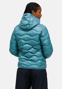 Turquoise gewatteerde jas met een doorgestikt ontwerp, voorzien van een capuchon en een gladde, glanzende textuur. De achterkant toont duidelijke golfpatronen en naden.