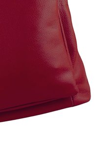 Sac en cuir rouge avec une texture lisse et une forme douce, légèrement arrondie. Il dispose d'une fermeture à glissière sur le dessus. Détails de couture visibles.