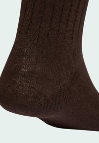 Bruna ribbstickade strumpor av stickat material, med en slät struktur och en nära passform runt ankeln som fångar fotens kontur.