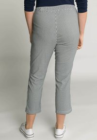 Pantaloni a scacchi bianco e nero con un design a gamba affusolata e cropped e una texture liscia, dotati di una vita e di spacco laterale all'orlo.