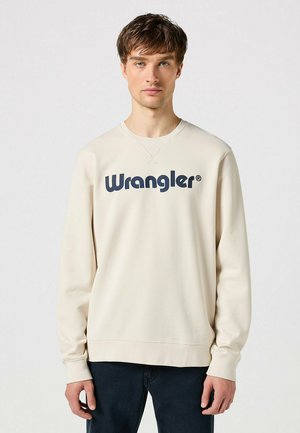Light beige sweatshirt with a crew neckline and long sleeves. Features bold navy "Wrangler" logo across the chest. Soft cotton material.