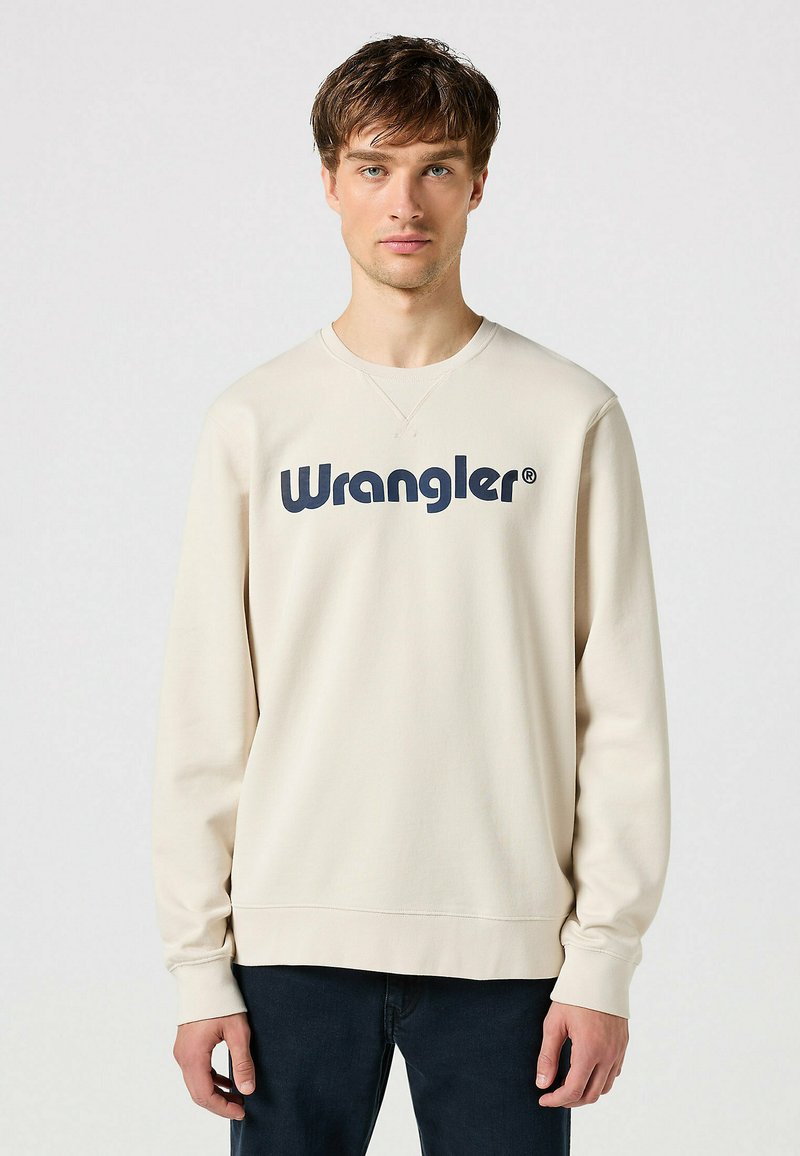 Felpa beige chiaro con scollo rotondo e maniche lunghe. Presenta il logo "Wrangler" in blu navy in evidenza sulla parte anteriore. Comodo materiale in cotone.