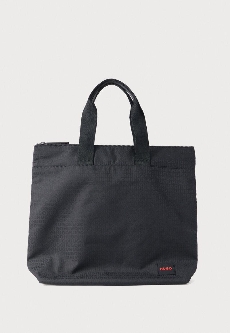 Schwarze Tragetasche aus strapazierfähigem Stoff mit zwei oberen Griffen. Verfügt über ein dezentes, geprägtes Logomuster und ein kleines rotes Markenetikett.