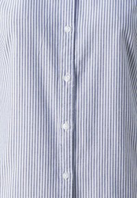 Blue and white striped button-up shirt, featuring a smooth fabric, classic collar, and six white buttons along the front.