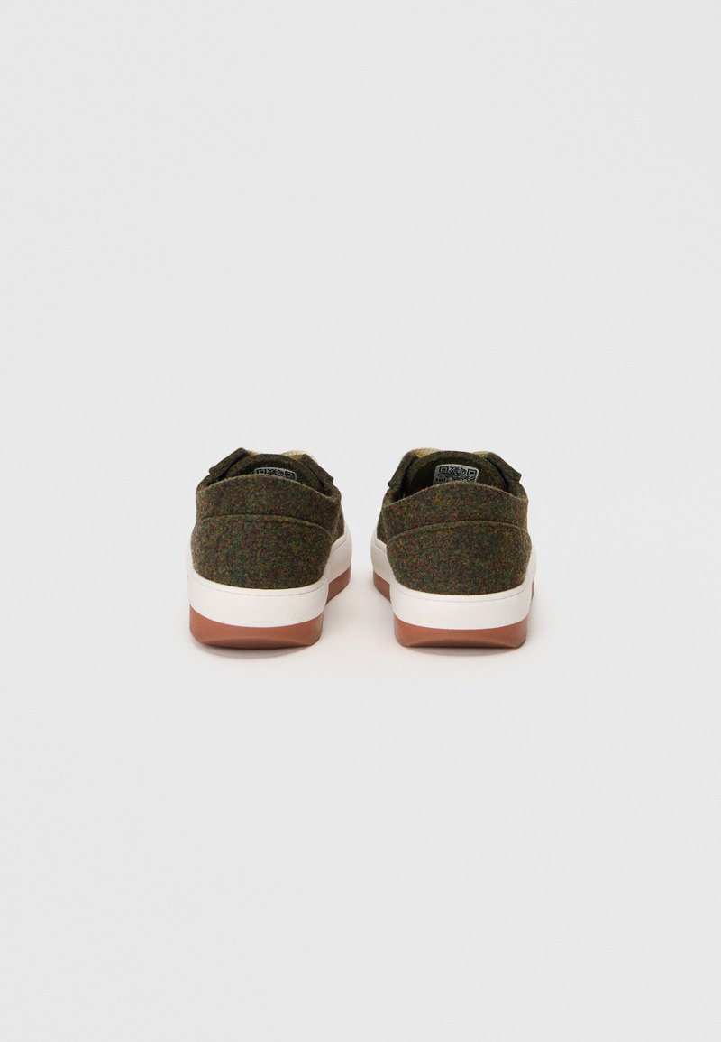 Et par lavtop sneakers med grønt tweed-stof, hvide mellemsåler og brune gummiydersåler vist fra bagsiden mod en ensfarvet baggrund.