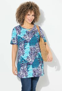 Kortærmet tunika i blå og lilla mønstre med geometriske og blomstrede designs, der har en v-hals og en vævet taske.