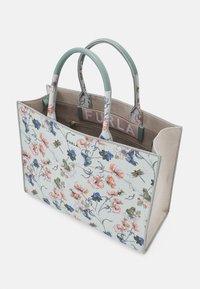 Torba tote w kwiatowy wzór z zielonymi uchwytami, wykonana z teksturowanego materiału. Charakteryzuje się wielokolorowymi kwiatami, wewnętrzną kieszenią i logo marki.