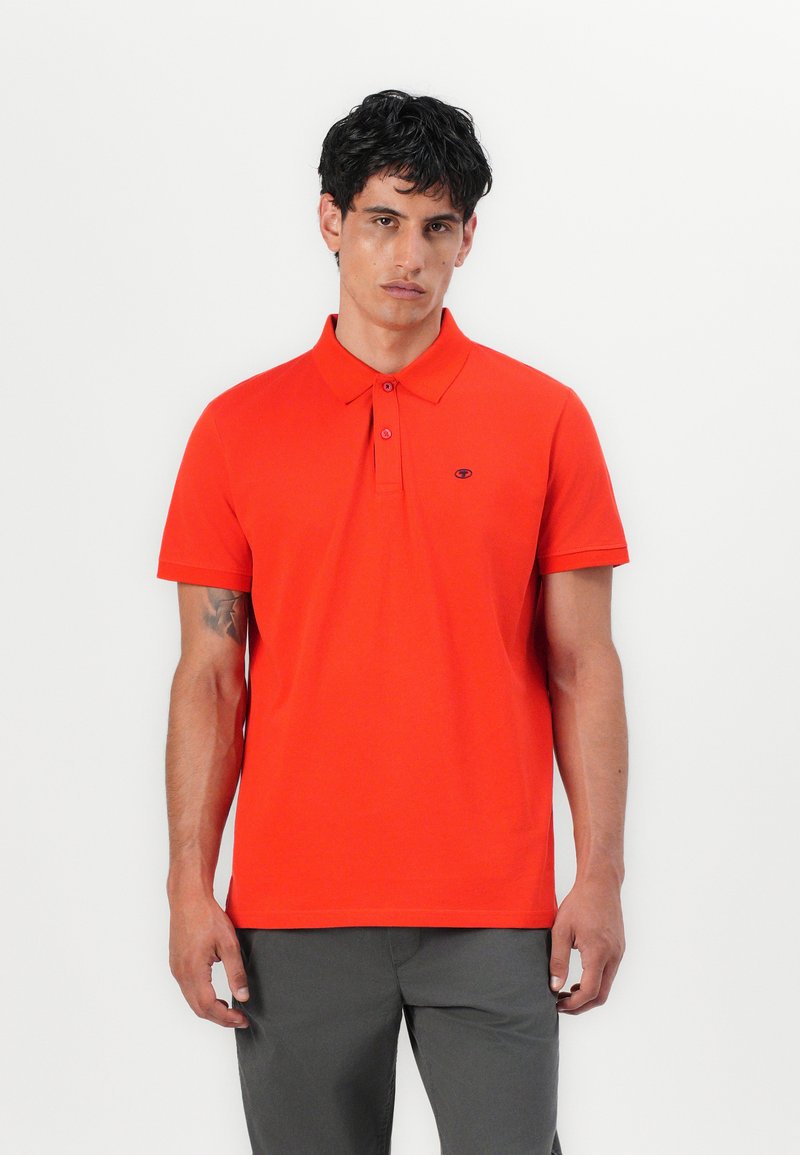 Rød polo-shirt lavet af glat stof, med en to-knaps placket, korte ærmer og et lille logo på venstre bryst.