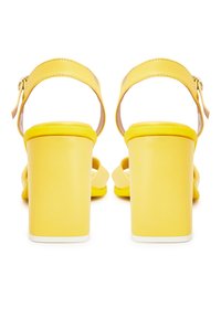 Gelbe High Heels Sandalen mit Blockabsatz, verstellbarem Knöchelriemen und glatter Textur. Offene Zehenpartie mit minimalistischen Stilelementen.