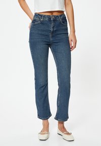 Mörkblå denimjeans med rak benmodell, utrustade med fem fickor, bälteshällor och en knapp i mässing som stänger i midjan.