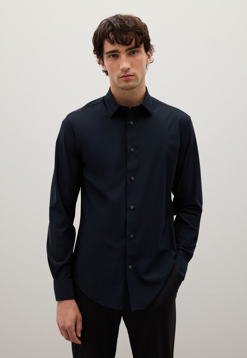 Camicia a maniche lunghe blu scuro con colletto classico, texture liscia e leggero lucido. Presenta sei bottoni e un orlo arrotondato.