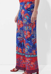 Blumenmuster-weite Hosen in Blau, Rot und Türkis, mit elastischem Bund und dekorativen Akzenten am Saum.