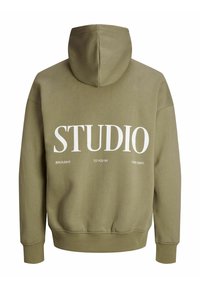 Alie žalia džemperis su dideliu baltu "STUDIO" užrašu nugarinėje pusėje ir papildomu tekstu žemiau minimalistiniame dizaine. Minkšta tekstūra.