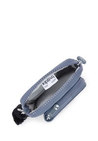 Liten blå Kipling dragkedjepåse med öppen huvudfack, synlig märkesetikett och svart nyckelring med pom-pom fästad.