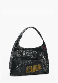 Mustast kangast õlakott, millel on grafitistiilis valge ja kollane tekst, tikkimismustrid ning punutud sang.