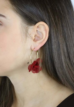 Orecchini a cerchio con fiori rossi realizzati in metallo con dettagli intricati. Il cerchio è dorato e presenta una chiusura sicura per un facile utilizzo.