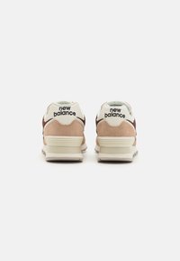 Baskets New Balance marron et crème en matériaux suède et mesh, avec un col rembourré, un branding minimal et des semelles texturées.