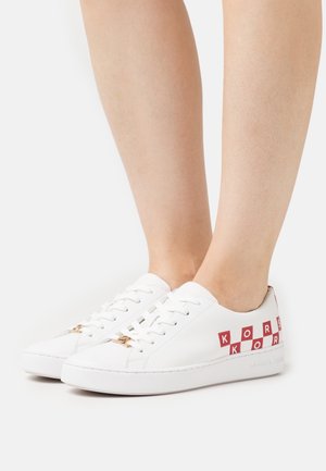 Sneakers in pelle bianca con testo rosso "KORS" e dettagli a scacchi, design con lacci piatti e sottile hardware dorato.