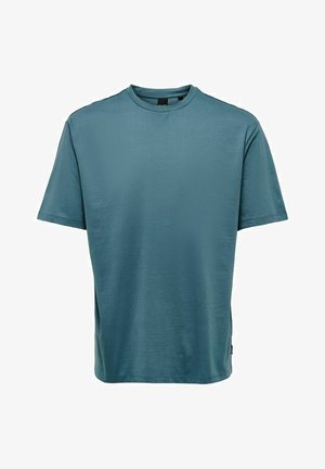 T-shirt a maniche corte, collo rotondo, di colore blu teal, realizzato in tessuto liscio con una vestibilità rilassata e dettagli minimi.