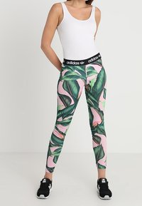 Legíny Adidas s růžovým podkladem a velkými zelenými palmami, černým elastickým pasem a přiléhavým střihem.