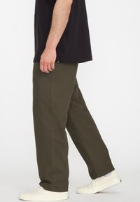 Olijfgroene broek gemaakt van een katoenmix, met een rechte pasvorm en zijzakken, gecombineerd met witte sneakers.