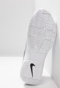 Bílá podrážka tenisky Nike se vzorem rybí kosti. Hladký plastový povrch s černým logem Nike na boku.