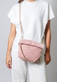 Borsa a tracolla in suede rosa con design trapuntato, pattina ripiegabile e tracolla a catena con accenti pastello.