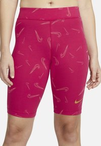 Fuksijų spalvos dviračių šortai iš tamprios medžiagos, puošta kreminės spalvos Nike logotipų raštu ir auksiniu Nike logotipu kairėje kojoje.