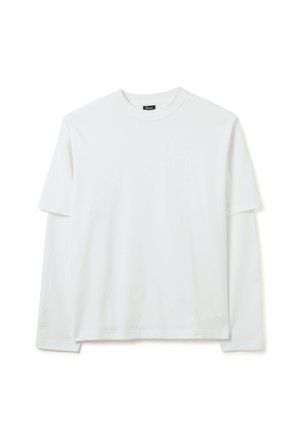 Camicia bianca a strati con maniche lunghe e sovrapposizione di maniche corte, collo a giro, e discreta ricamatura del marchio vicino al polsino sinistro.