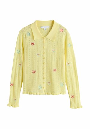 Żółty dziergany kardigan z spiczastym kołnierzem, ozdobiony wielokolorowymi haftowanymi sercami i kokardkami. Zapinany na guziki z przodu, ze ściągaczowymi mankietami.