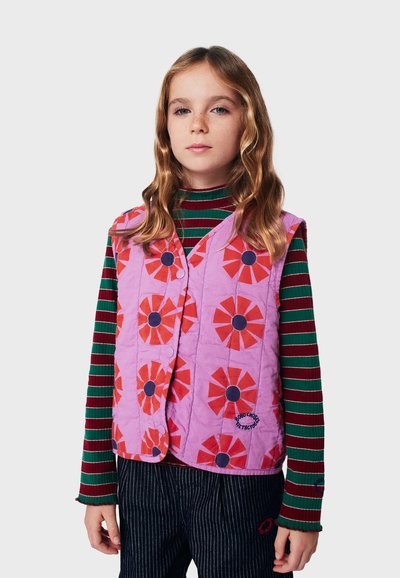 Gestepptes Westchen in Helllila mit großen roten und schwarzen Blumenmustern. Verfügt über vordere Knöpfe und wird über einem gestreiften Langarmshirt getragen.