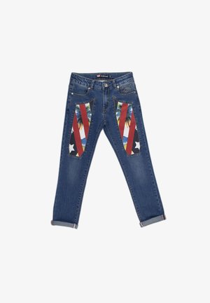 Jean en denim avec une teinte bleu moyen. Présente des inserts en tissu à motifs rouges et noirs avec des palmiers et des montagnes. Revers roulés à l'ourlet.