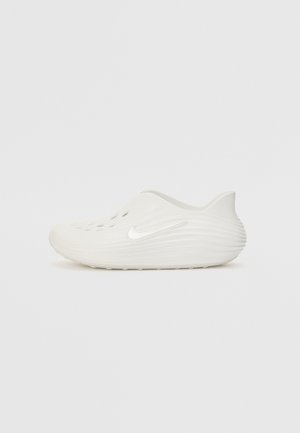 Botte blanche à enfiler avec un dessus texturé, des découpes circulaires pour la ventilation et un logo en forme de swoosh sur le côté. Design lisse et arrondi avec une semelle plate.